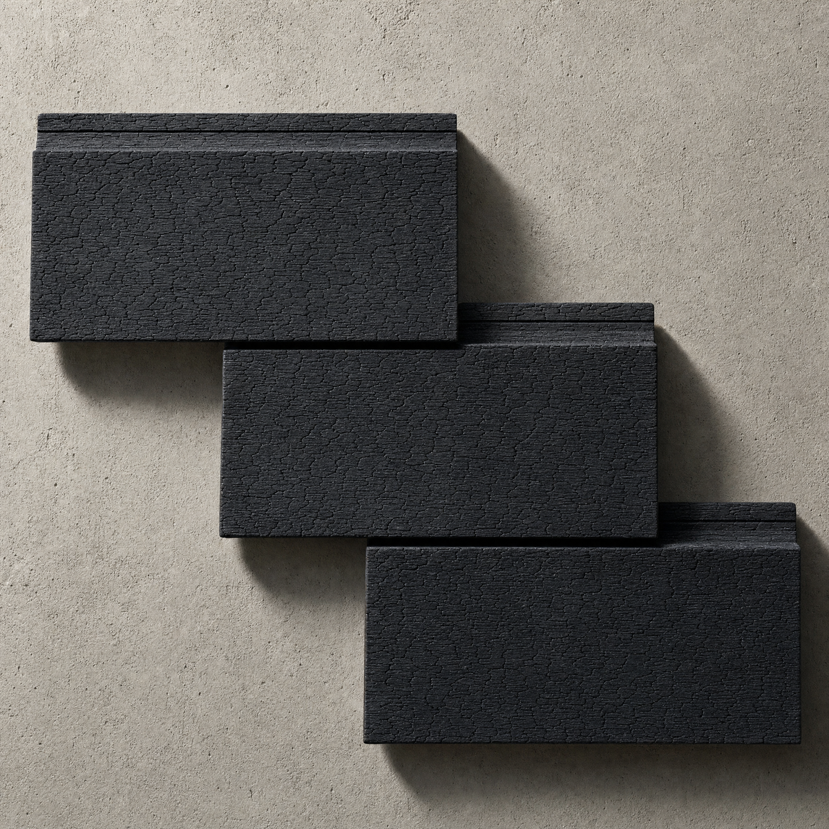 Shou Sugi Ban Australian Hardwood BAL-29 charred cladding boards on a warm raw-concrete background, showing deep alligator-skin char texture.